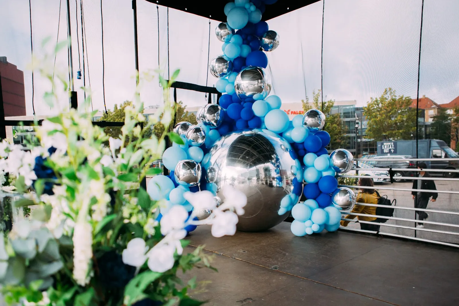 Ballondekoration i lyseblå og koboltblå med stor spejlkugle i hjørnet af scenen ved AAU København