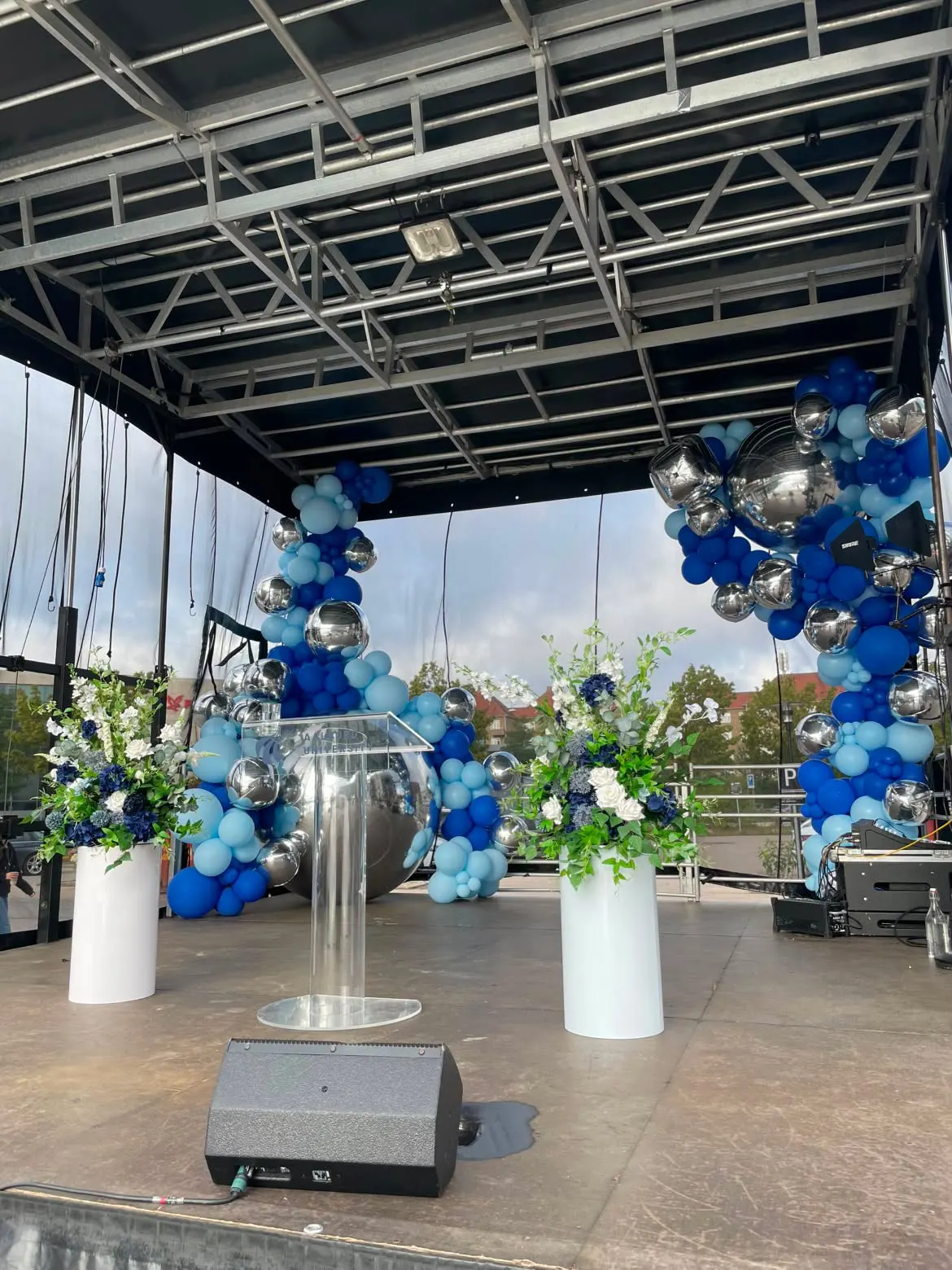 Scenedekoration med balloner, spejlkugler og blomsteropsætninger set fra scenekanten