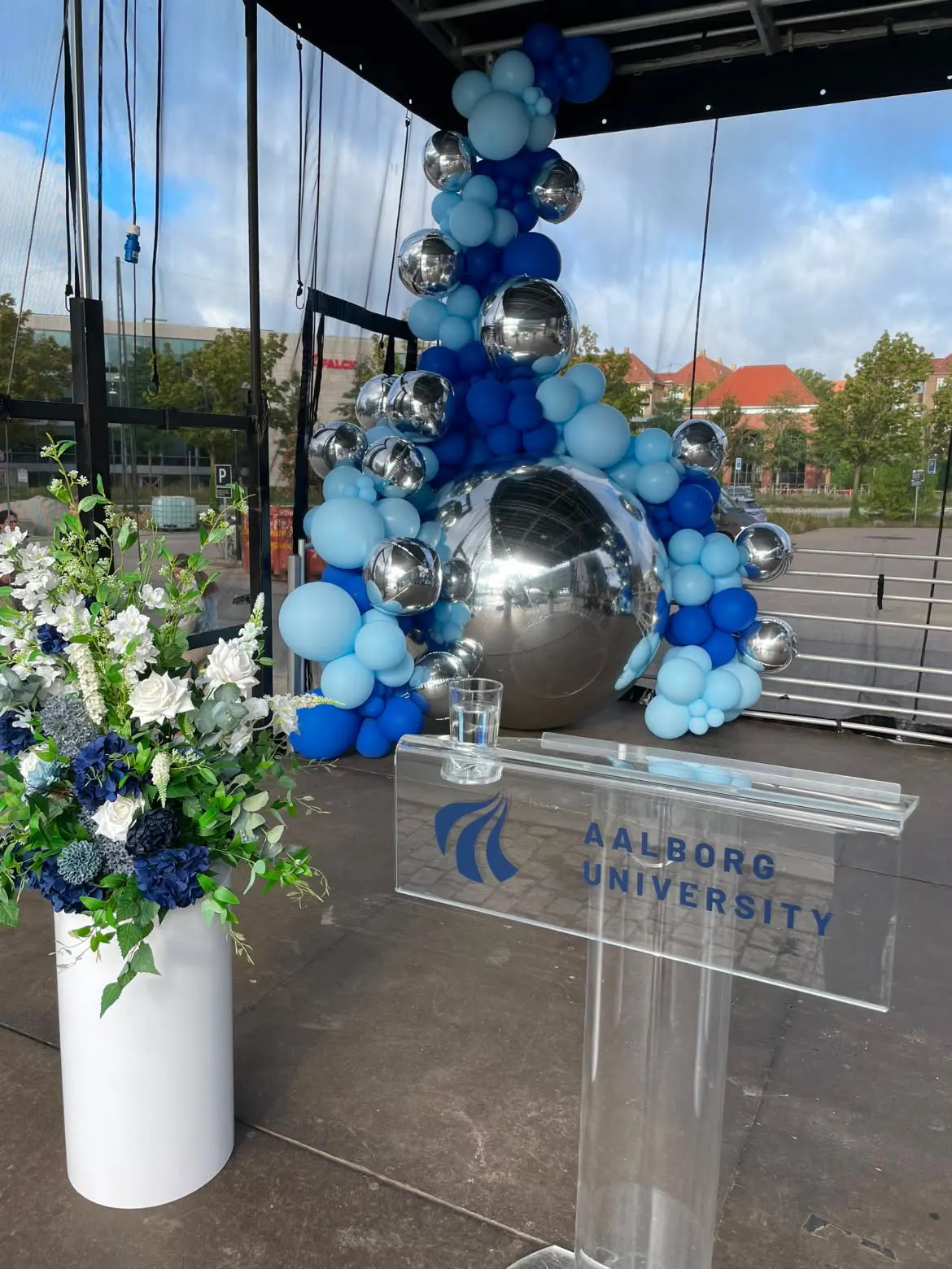 Talerpult med Aalborg University-logo foran ballonskulptur med stor spejlkugle