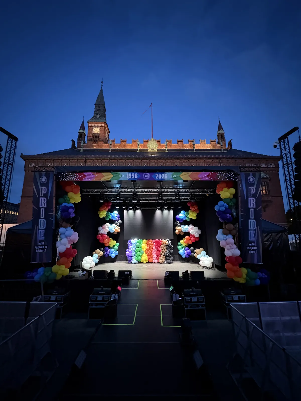 Hovedscenen på Rådhuspladsen i aftenlys med ballonguirlander og ballonvæg i Pride-farverne foran Rådhuset